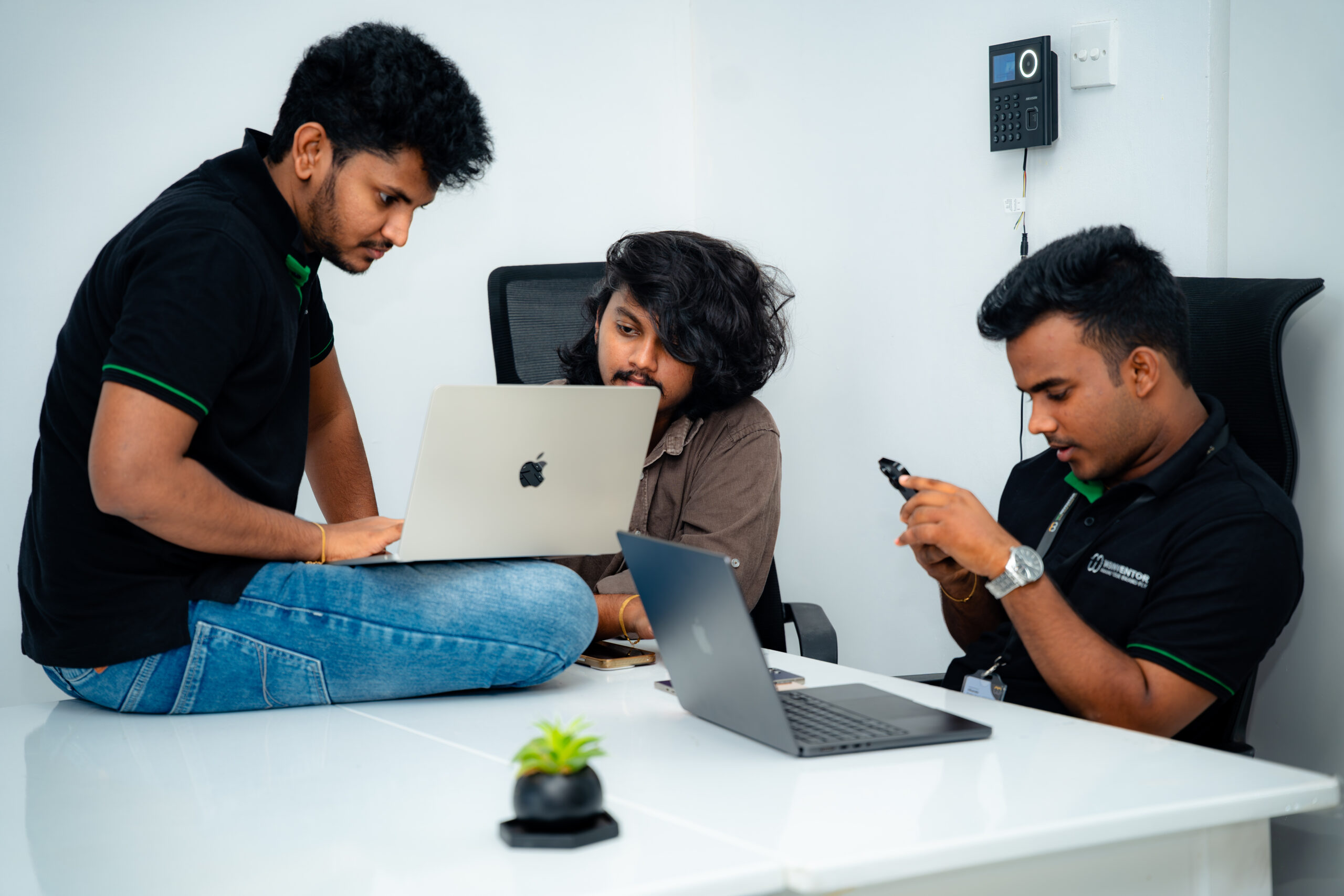 Three W3Inventor marketers brainstorming around laptops and a smartphone in the Colombo office