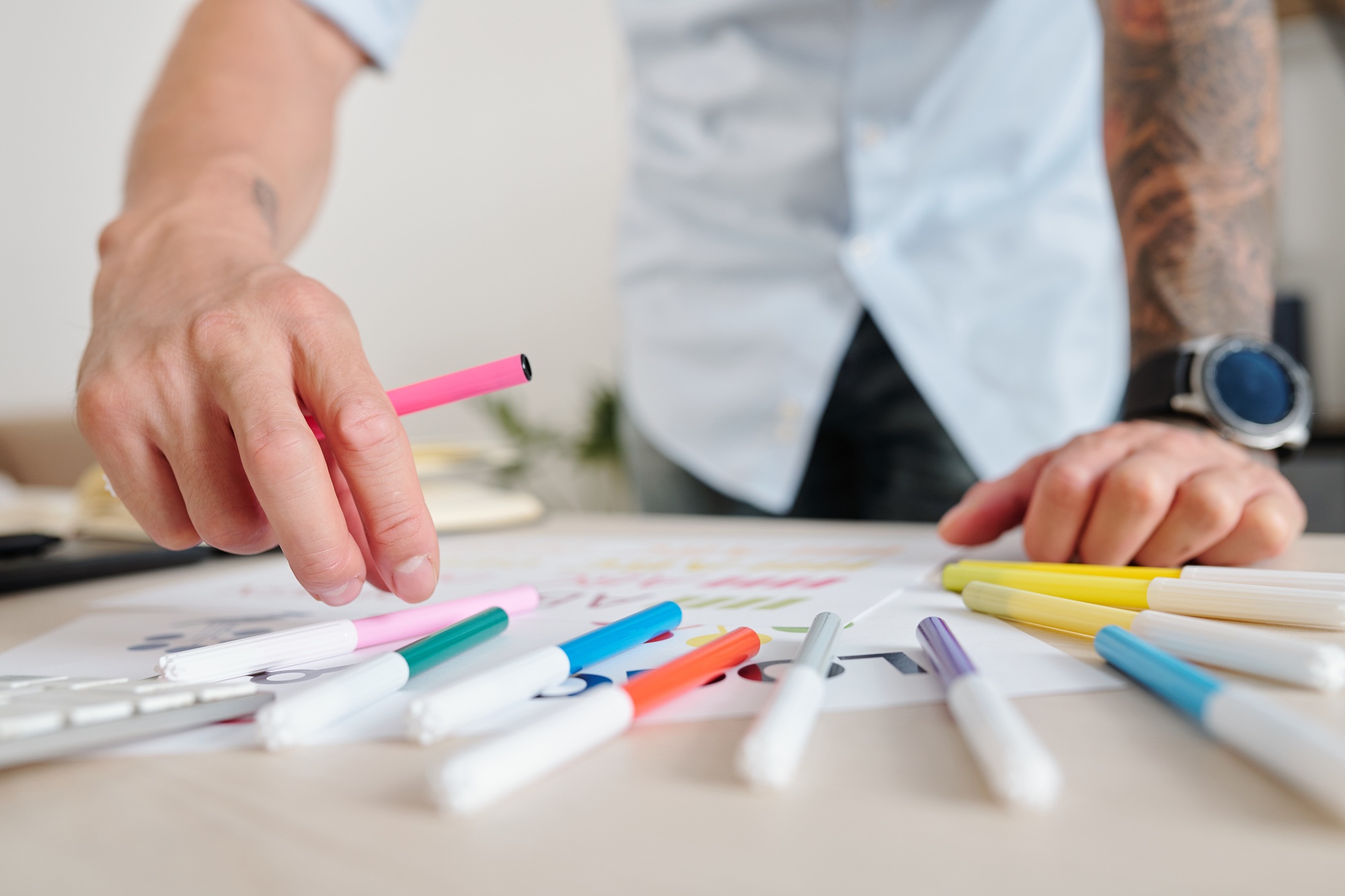Designer picking a pink marker from a spread of colourful pens while sketching brand colour palettes at W3Inventor