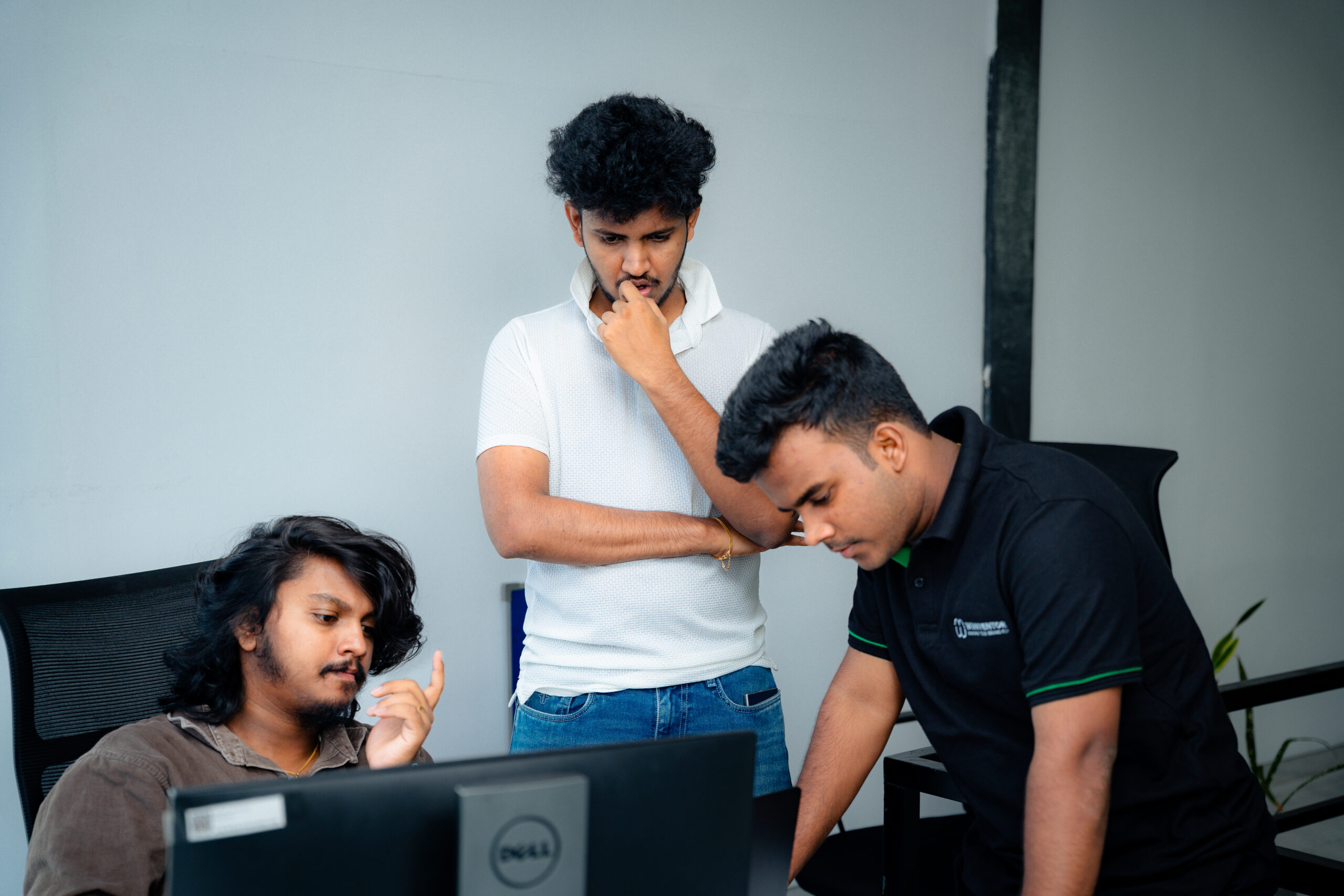 Three W3Inventor colleagues studying a screen during a design review session