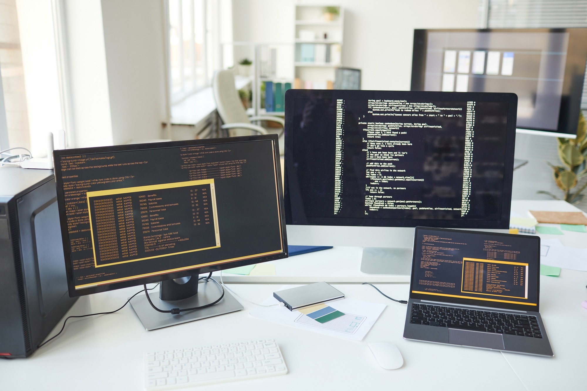 Multiple monitors and a laptop running backend code and terminal outputs in W3Inventor’s web development workspace